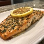 Close-up of a beautifully seasoned air fryer salmon fillet topped with a charred lemon slice.