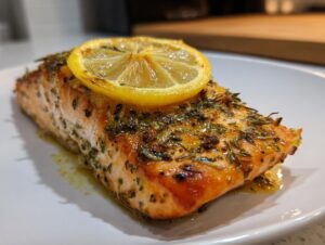 A perfectly cooked piece of air fryer salmon seasoned with herbs and topped with a caramelized lemon slice.