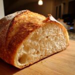 Close-up of a freshly baked french bread loaf cut in half, showing the airy, open crumb structure.
