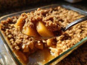 A spoonful of warm, gooey baked apples and crunchy topping from an apple crisp recipe.