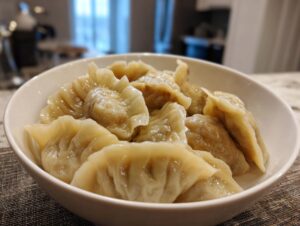 A close-up of a white bowl filled with freshly steamed Traditional Chinese Dumplings.