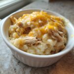 A close-up of a single serving of creamy chicken and rice casserole topped with melted cheddar cheese.