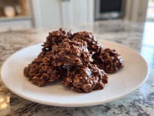 A close-up of several rich, chocolatey no bake cookies piled on a white plate.