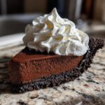 A perfect slice of Christmas chocolate cream pie featuring a rich dark filling and thick whipped cream topping.