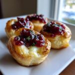 Four golden baked cranberry brie bites topped with glistening cranberry sauce and fresh thyme.