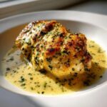 A golden-brown seared chicken breast swimming in a rich, creamy lemon sauce speckled with fresh parsley.