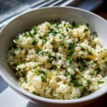 Close-up of fluffy cauliflower rice seasoned and topped generously with chopped fresh parsley.