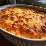Hot, bubbly Buffalo chicken dip with a golden-brown, cheesy crust, served in a white ceramic baking dish.