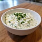 Close-up of creamy homemade tartar sauce recipe garnished with fresh chopped parsley in a white bowl.
