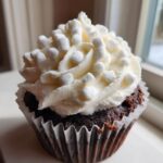 Close-up of a rich chocolate cupcake topped with white frosting and mini marshmallows, perfect for hot chocolate cupcakes.