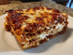 Close-up of a hearty slice of Lasagna with Cottage Cheese showing layers of pasta, meat sauce, and white cheese filling.
