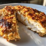 Close-up of a cooked chicken breast cut in half showing juicy white meat and a golden, seasoned crust, demonstrating melt in your mouth chicken.