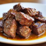 Close-up of tender, juicy crockpot steak cubes coated in a rich, savory brown sauce.