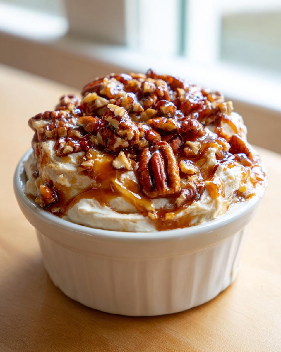 A creamy pecan pie dip topped generously with candied pecans and caramel sauce in a white ramekin.