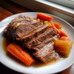 Slices of tender pot roast served with carrots and gravy, perfect for Sunday dinner ideas.