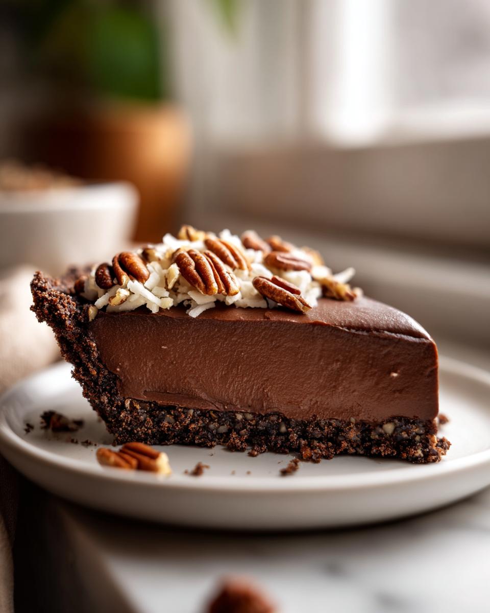 Close-up of a slice of rich german chocolate pie with a dark crust, topped with coconut and pecans.