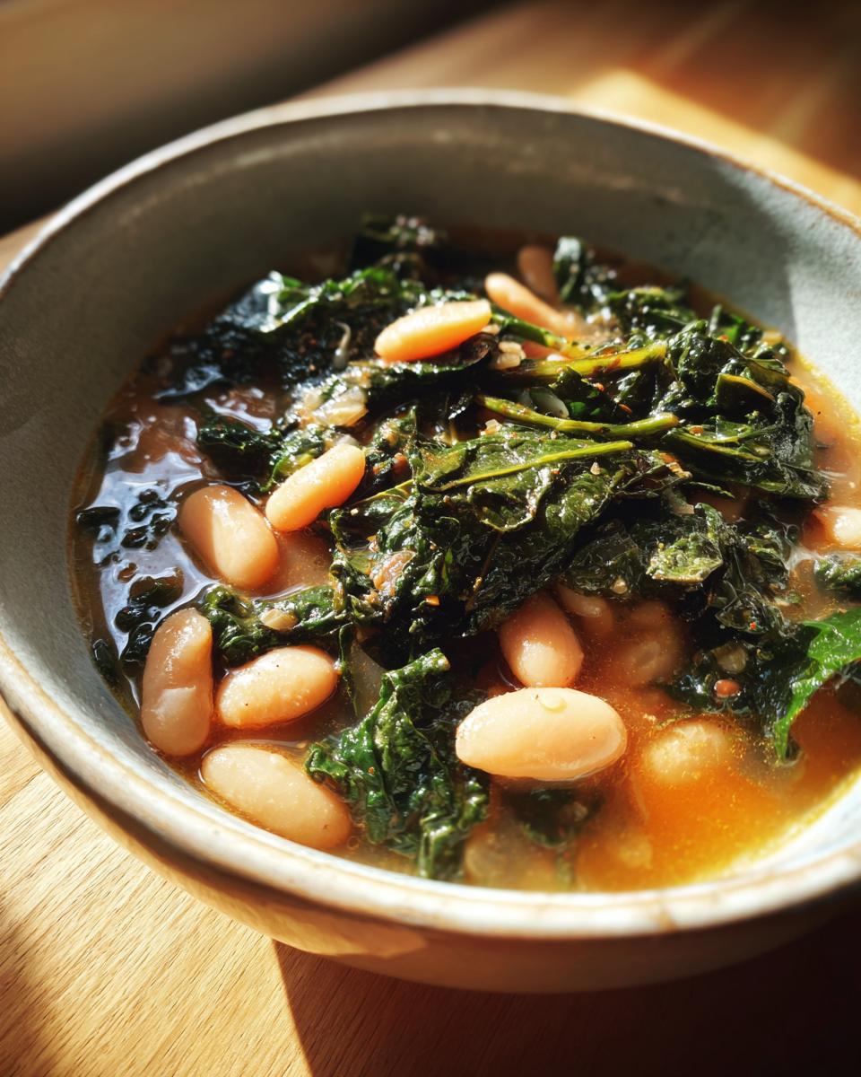 Close-up of a rustic bowl filled with rich, brothy tuscan white bean soup featuring cannellini beans and dark leafy greens.