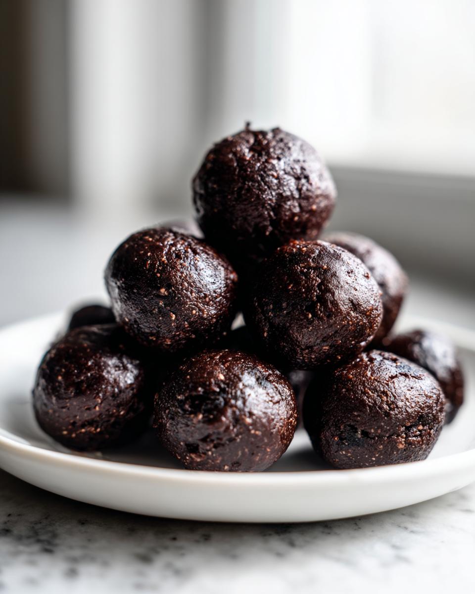 A stack of dark, rich, no-bake Oreo balls piled high on a small white plate.