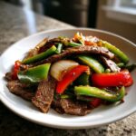 Close-up of a serving of amazing 30-minute pepper steak with beef, red and green bell peppers, and onions.