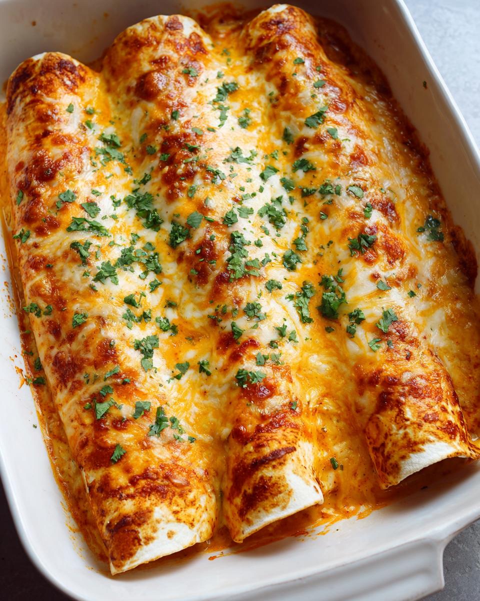 Close-up of three baked shrimp enchiladas covered in melted orange and white cheese and sprinkled with fresh cilantro.