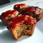 Close-up of a delicious mini meatloaf muffin with a bite taken out, topped with shiny red glaze.