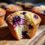 A close-up shot of a freshly baked blueberry muffin with a bite taken out, revealing moist crumb and juicy blueberries.