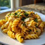 Close-up of cheesy chicken pasta made with rotini, covered in rich orange sauce and topped with fresh parsley.