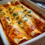 Close-up of three baked shrimp enchiladas covered in melted orange and white cheese and fresh parsley.