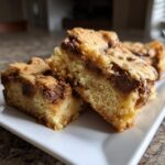 Close-up of two thick, chewy cake mix cookie bars loaded with melted chocolate chips on a white plate.