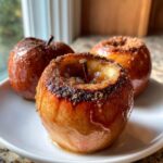 Close-up of a perfectly baked apple, cored and topped with caramelized cinnamon sugar.