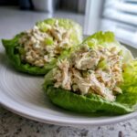 Two lettuce cups filled with creamy cottage cheese chicken salad, garnished with celery pieces.