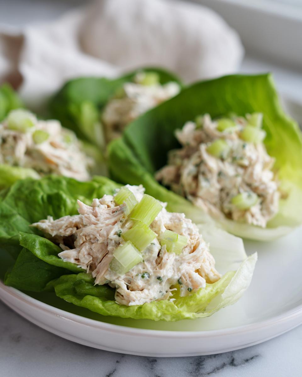 Close-up of cottage cheese chicken salad served in crisp lettuce cups, topped with diced celery.