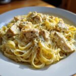 A close-up, appetizing shot of creamy chicken alfredo pasta featuring fettuccine noodles and chunks of seasoned chicken.