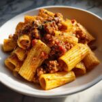 Close-up of creamy sausage pasta made with rigatoni tubes coated in a rich, meaty sauce.