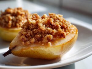 A close-up of a halved, baked pear topped generously with a golden brown, crunchy crumble mixture, part of a divine baked pears recipe.