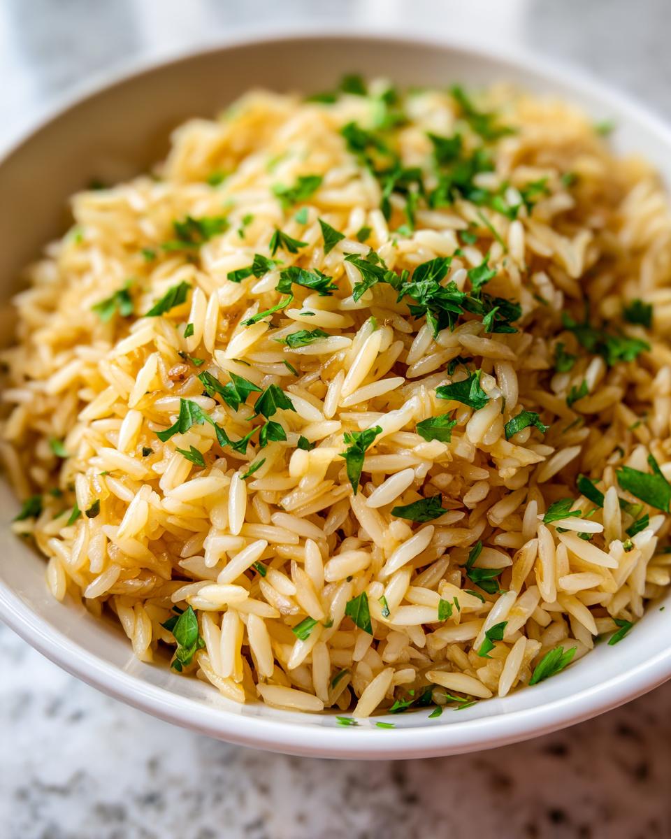 Close-up of fluffy rice pilaf, seasoned and topped with fresh chopped parsley, served in a white bowl.