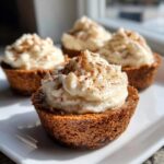 A close-up of one of the gingerbread cheesecake cups topped with whipped cream and sprinkled with cinnamon.