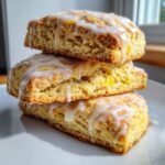 A stack of three delicious lemon scones topped with a thick white glaze, showcasing their crumb texture.