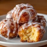 Close-up of several gooey cinnamon roll bites coated in cinnamon sugar and drizzled with white icing, one has a bite taken out.