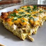 Close-up of a serving of green chile chicken enchiladas casserole topped with melted cheese and cilantro.