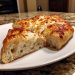 Cross-section of thick-crust homemade pizza showing airy dough and gooey, browned mozzarella cheese.