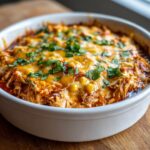Close-up of hot chicken enchilada dip topped with melted cheese, corn, and fresh cilantro.