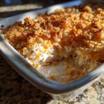 Close-up of a baked hot chicken salad casserole with a creamy interior and a crunchy, golden-brown topping.