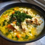 Close-up of a vibrant bowl of Lemon Ginger Turmeric Chicken and Rice Soup, topped with shredded chicken and parsley.