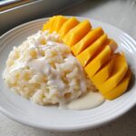 A serving of delicious mango sticky rice topped with rich coconut cream sauce.