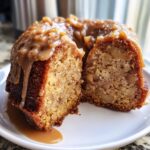 A slice cut from a moist apple bundt cake, generously topped with a thick caramel sauce.