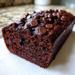 Close-up of a moist, dark chocolate banana bread loaf topped generously with melted chocolate chips.