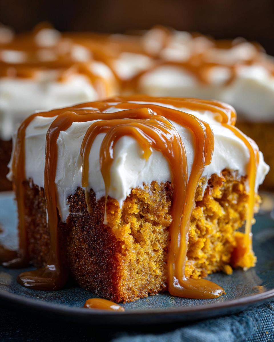 Close-up of a moist slice of pumpkin poke cake topped with cream cheese frosting and drizzled with caramel sauce.