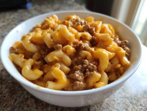 Close-up of a white bowl filled with creamy homemade hamburger helper, featuring elbow macaroni and seasoned ground beef.