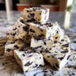 A tempting stack of white chocolate Oreo fudge squares loaded with crushed chocolate cookies, perfect for a no-bake treat.